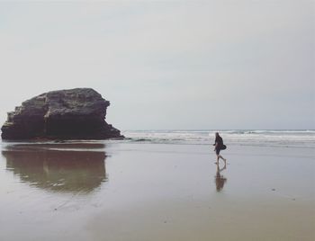 Full length of man walking on shore at beach against sky