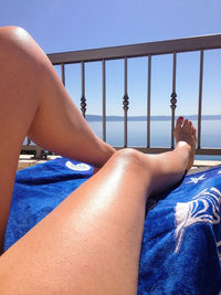 Low section of sensual woman relaxing on deck by sea against sky