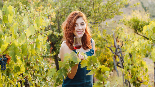Happy woman with glass of wine in the vineyard
