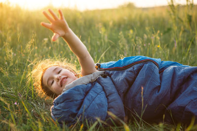 Cute girl in sleeping bag on field