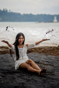 Portrait of smiling young woman at beach against sky