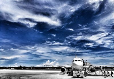 Airplane on airport runway against sky