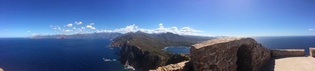 Panoramic view of sea and mountains against blue sky