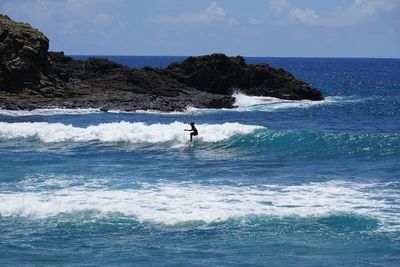 Man surfing in sea against sky