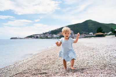 Full length of cute boy on beach against sky