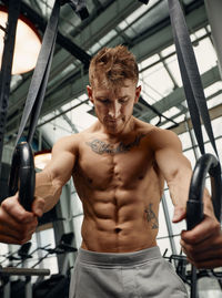 Portrait of shirtless man exercising in gym