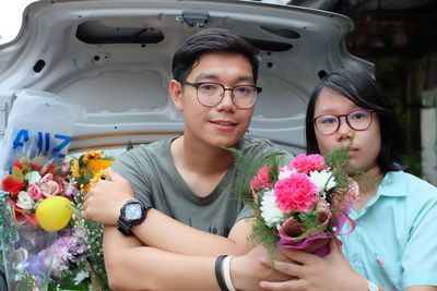 Portrait of siblings with bouquets sitting in car trunk