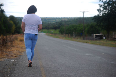 Rear view of man walking on road