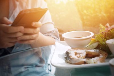 Woman is sending photos on social media with salmon grilled salad menu on desk 