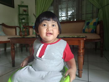 Portrait of cute girl sitting on chair at home