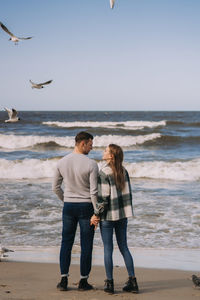 Rear view of friends standing on beach