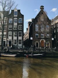 Canal by buildings in city against sky