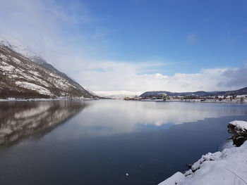 Scenic view of lake by snowcapped mountains against sky