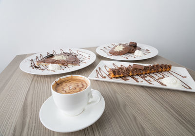 Close-up of coffee cup and desserts served on table