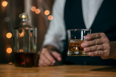 Midsection of man drinking glass on table