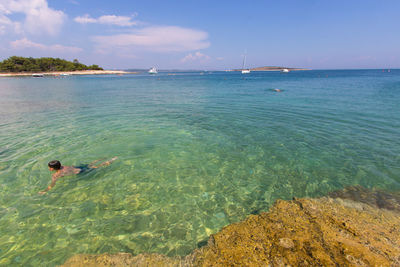 Man swimming in sea against sky