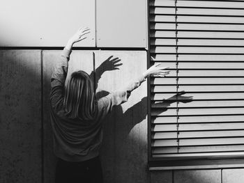Rear view of woman standing against wall