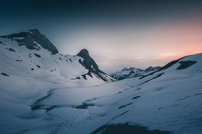 Scenic view of snowcapped mountains against sky during sunset