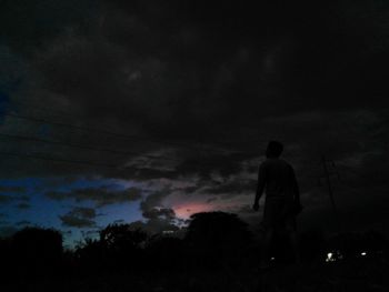 Low angle view of silhouette man standing against sky at night