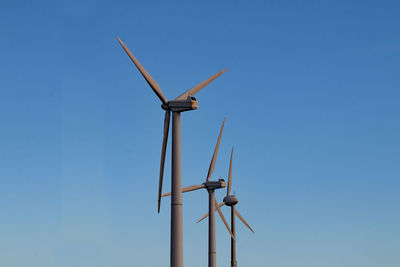 Low angle view of windmill against clear blue sky