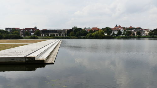 Buildings by lake against sky