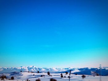 Scenic view of snowcapped mountains against clear blue sky