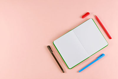 Directly above shot of diary and pens on pink background