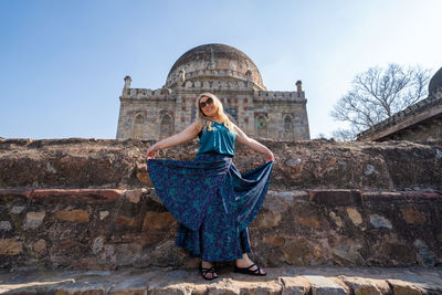 Young woman with umbrella standing against built structure