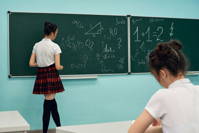 Asian high school girl solves geometry on the blackboard