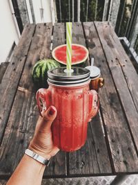 Close-up of hand holding drink on table