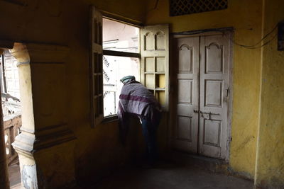 Rear view of man standing at entrance of building