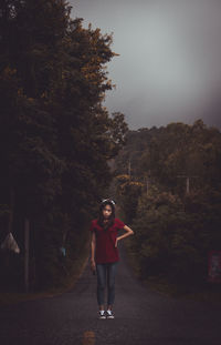 Portrait of woman standing by tree against sky