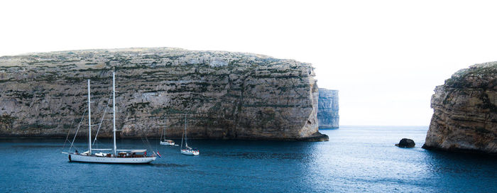 Boats sailing on sea against clear sky