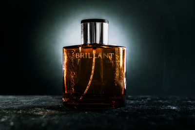 Close-up of glass bottle on table against black background