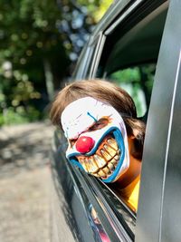Close-up of boy wearing spooky mask in car