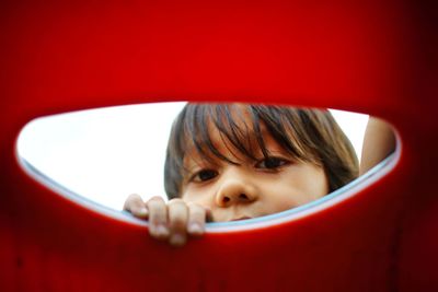 Close-up portrait of cute boy looking through outdoor play equipment