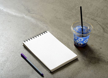 High angle view of note pad with drink on table