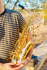 Midsection of man holding saxophone