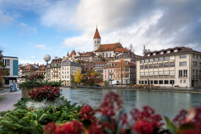 Buildings by river against cloudy sky