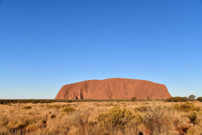 Scenic view of arid landscape against clear blue sky