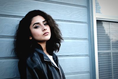 Portrait of beautiful woman wearing leather jacket against wall