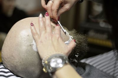 Cropped hands of barber shaving man at salon