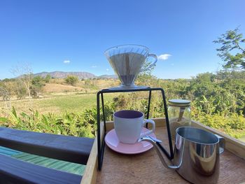 Coffee cup on table against clear blue sky