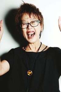 Close-up portrait of cheerful mature woman by wall