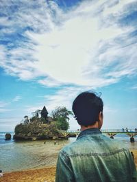 Rear view of man in sea against sky