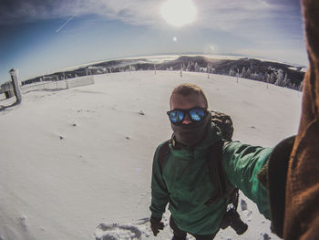 Selfie portrait of man standing on snow covered field