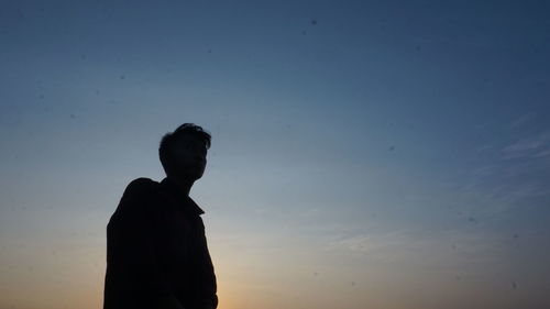 Silhouette man looking at sunset sky