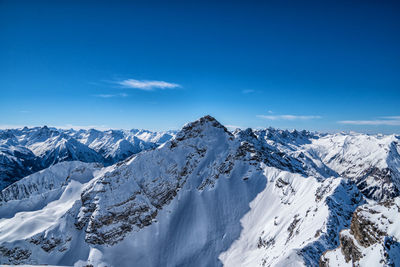 Scenic view of snowcapped mountains against blue sky