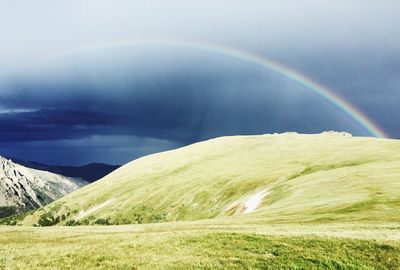 Scenic view of field against rainbow in sky