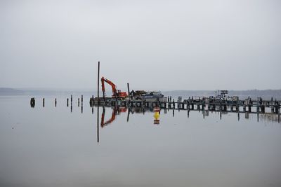 Wooden posts in sea against clear sky